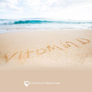 A beach shore with the word "vitamin D" written out in the sand
