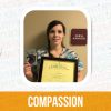 Kari Ward is smiling and holding up her Employee of the Month award, with the word "compassion" printed beneath