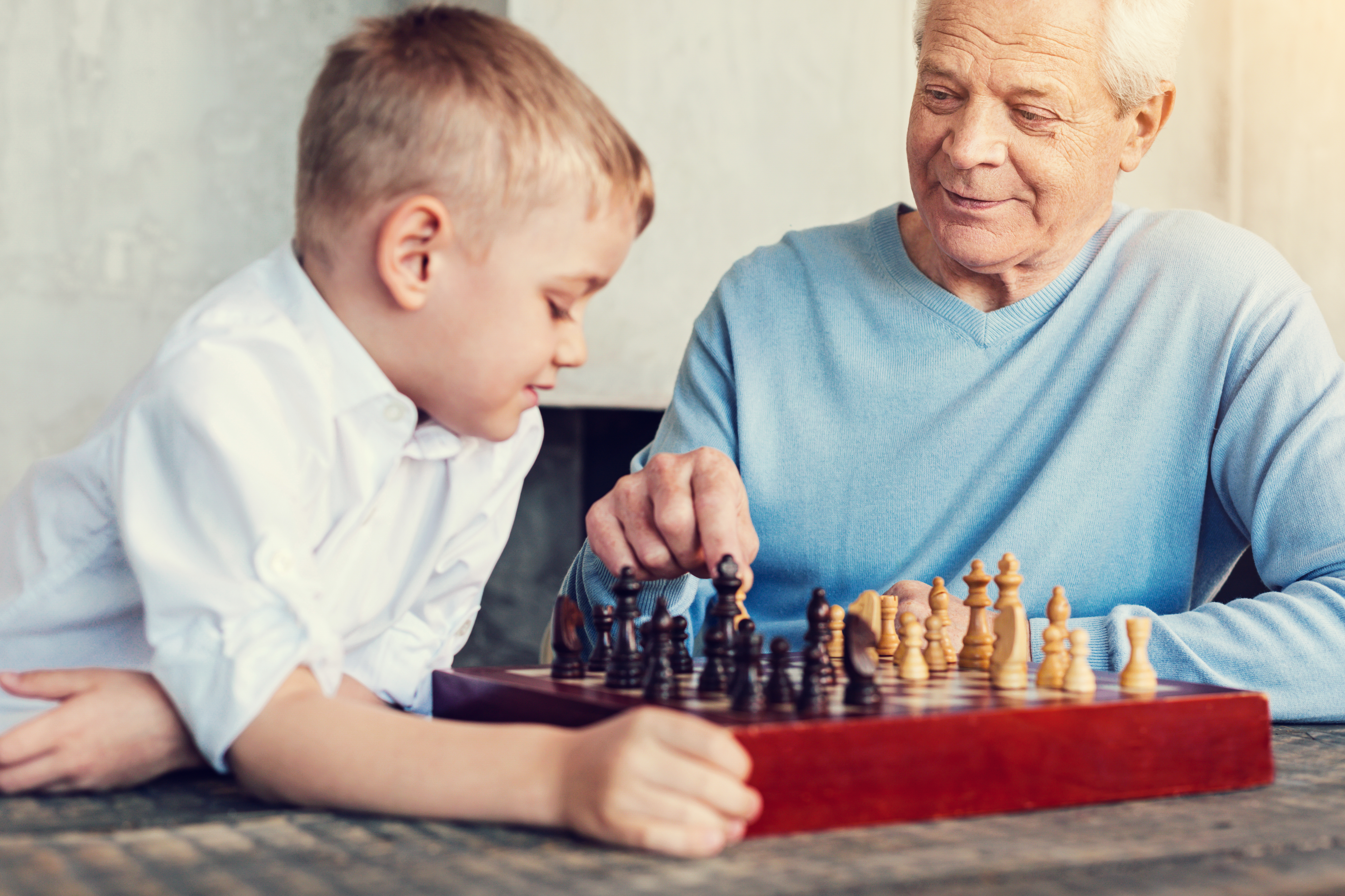 A young boy and an elderly man are enjoying a game of chess together