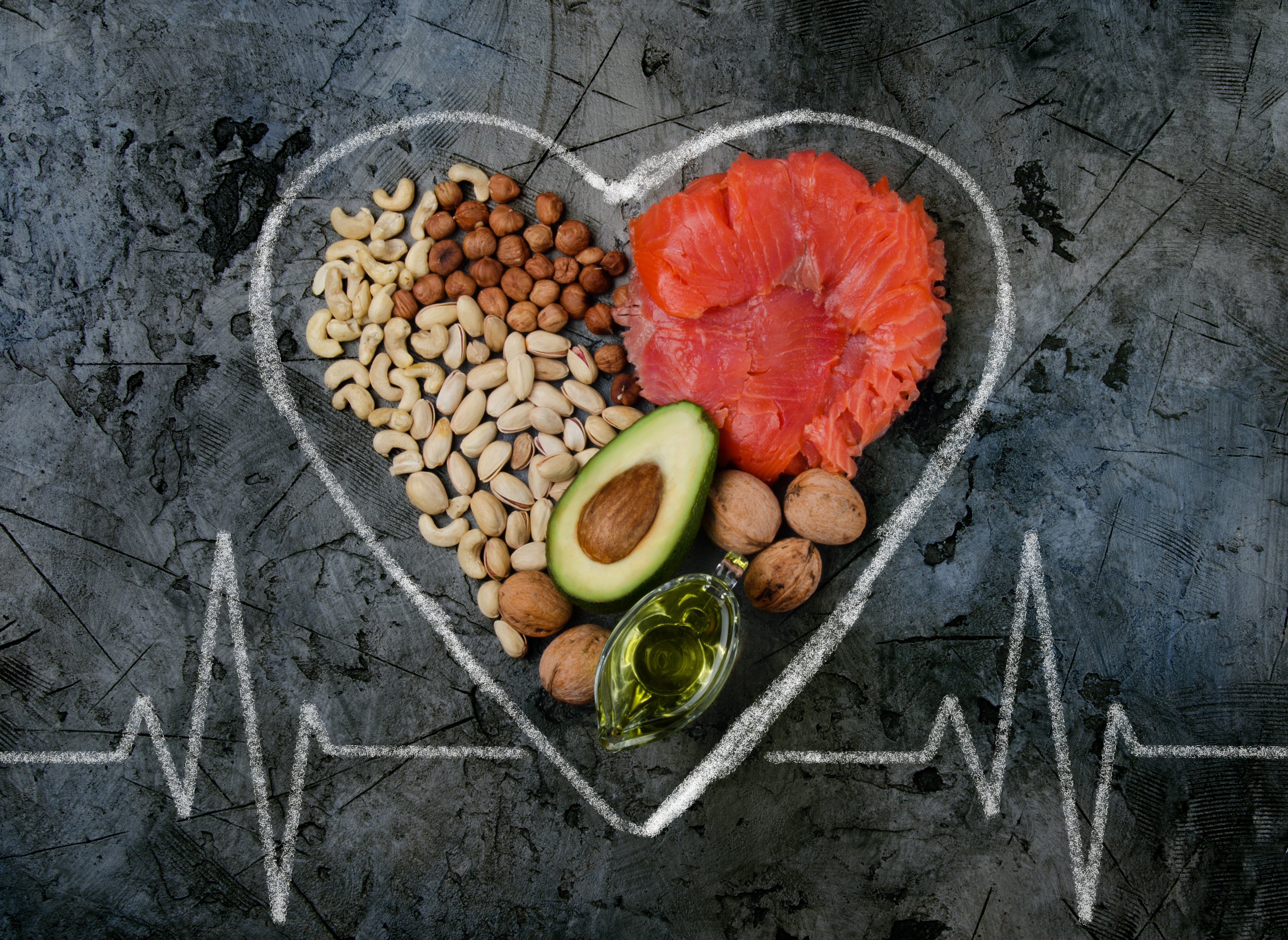 Nuts, almonds, avocado, olive oil, and salmon sit inside the outline of a heart
