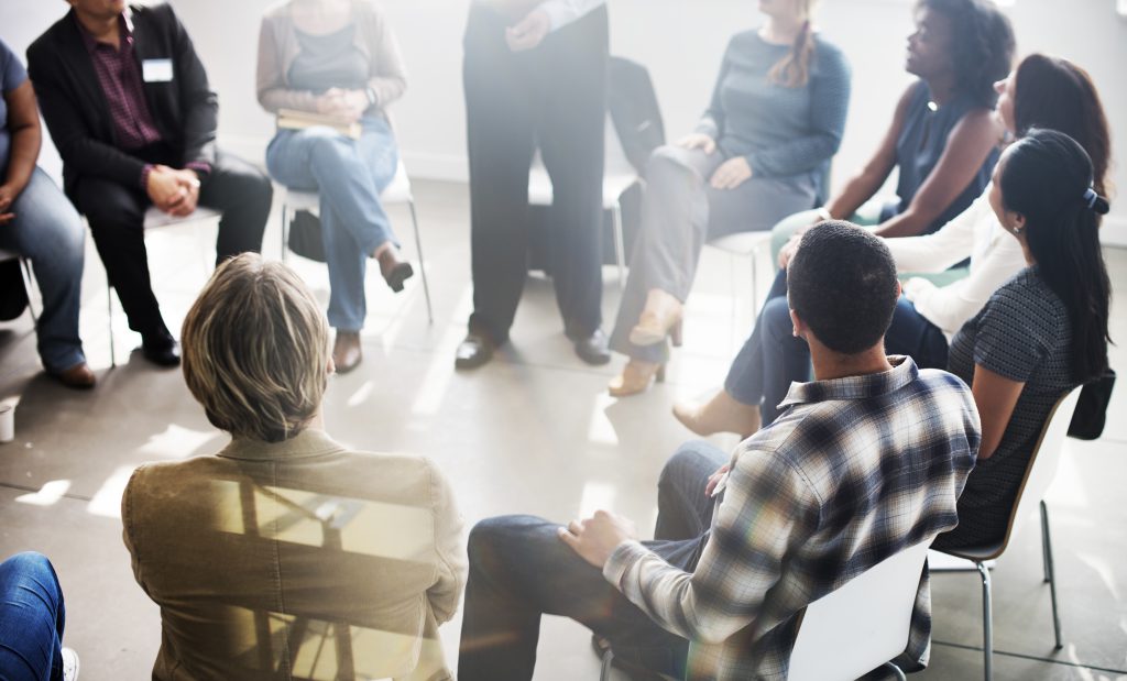 Men and women sit in a circle at a support group